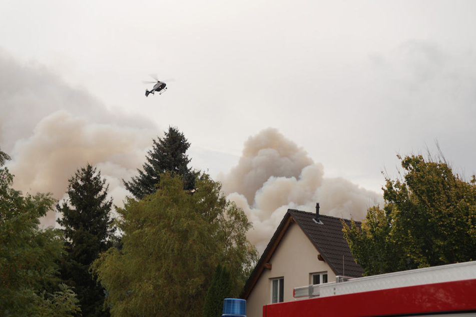 Ein Polizei-Hubschrauber kreist über den dichten Rauchwolken neben dem Ort Frohnsdorf.