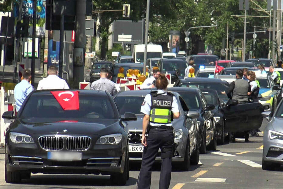 Eine Polizistin steht vor den Fahrzeugen eines türkischen Hochzeitskorsos.