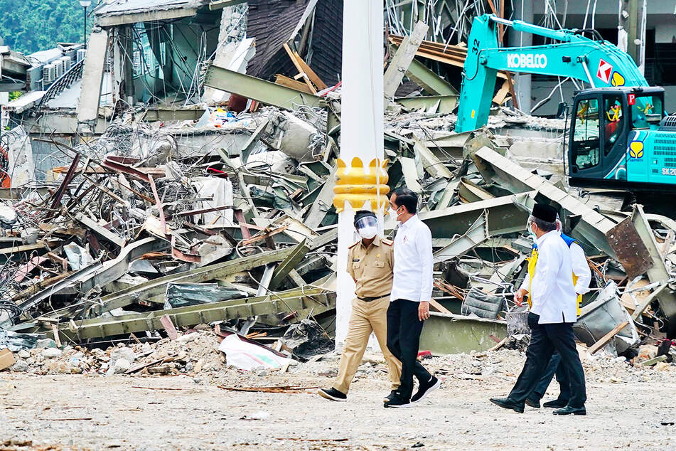 Präsident Joko Widodo (M) spricht mit einem Beamten, während er ein erdbebengeschädigtes Regierungsgebäude in Mamuju im Westen der indonesischen Insel Sulawesi inspiziert.