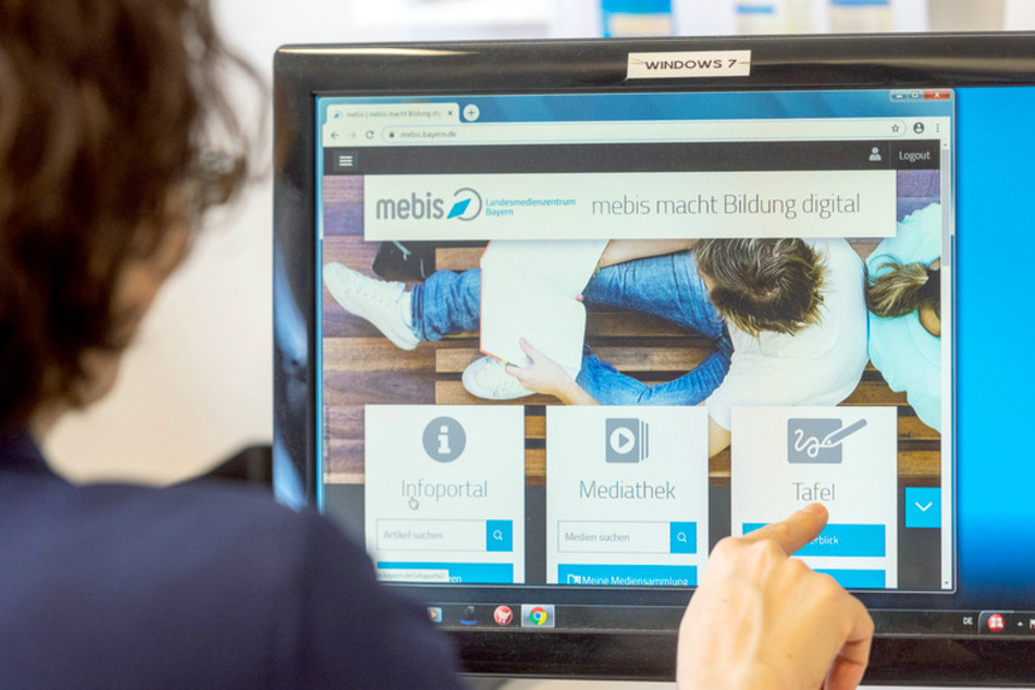 Eine Lehrerin sitzt vor einem Computermonitor mit dem Programm "mebis – Landesmedienzentrum Bayern".