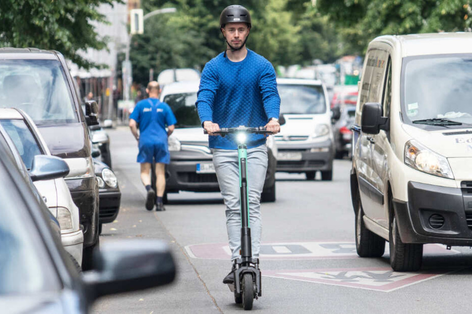 Ein Mann fährt mit einem E-Scooter auf der Straße. (Symbolbild)