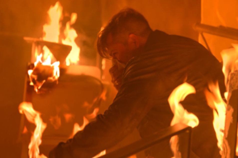 Als Leon im Mauerwerk ankommt, brennt das Club-Restaurant bereits lichterloh. Er versucht John aus den Flammen zu retten.