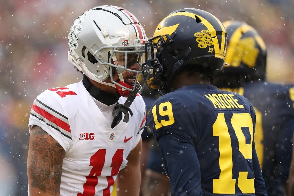 Jaxon Smith-Njigba of the Ohio State Buckeyes and Rod Moore of the Michigan Wolverines trash talk each other during their 2021 showdown at Michigan Stadium.