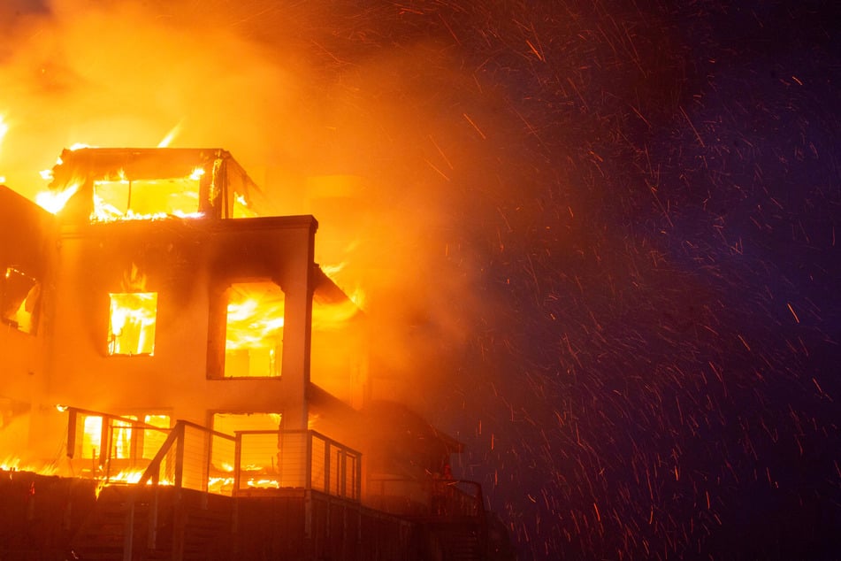 Flames rise from a structure as the Palisades Fire burns during a windstorm on the west side of Los Angeles, California, on January 8, 2025.