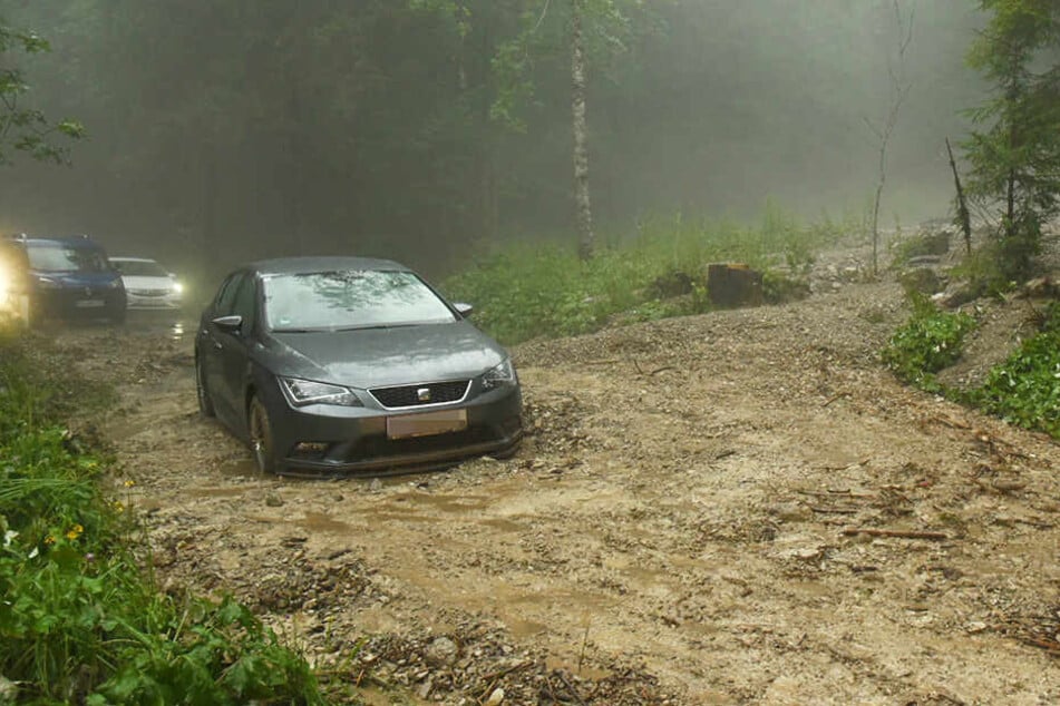 Nach heftigen Gewittern steht ein Auto in einer Mure mit Geröll und Schlamm im Bereich Kaiserbachtal.