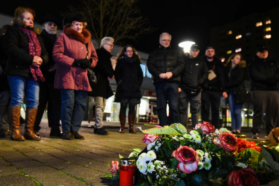 Mehrere Menschen legen Blumen und Kerzen in der Nähe eines Tatorts in Hanau nieder.