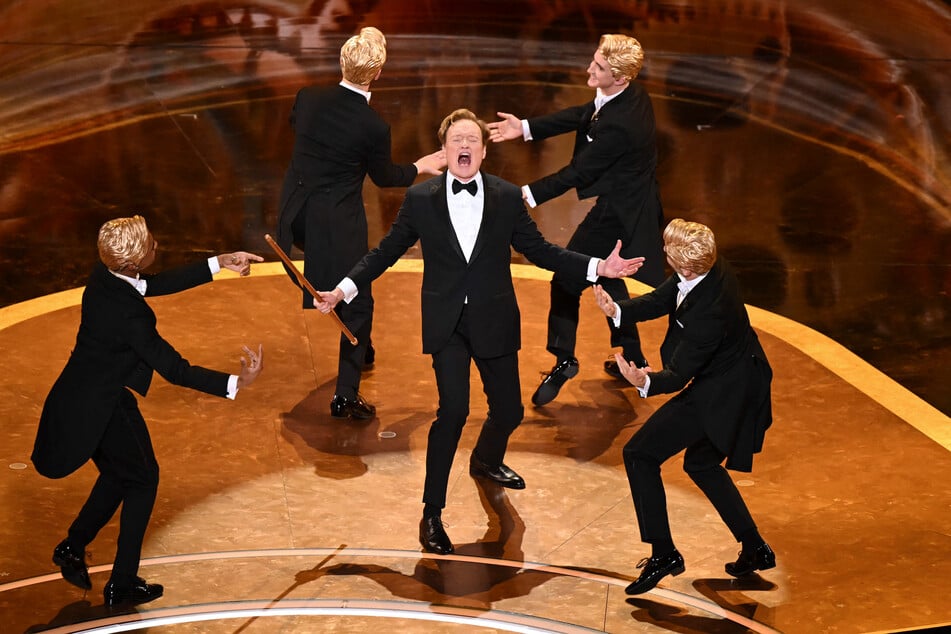 Conan O'Brien's (c.) first Oscars stint – which included a lively opening monologue, a quirky musical number, and a surreal pre-taped riff on satirical body-horror flick The Substance – earned wide praise.