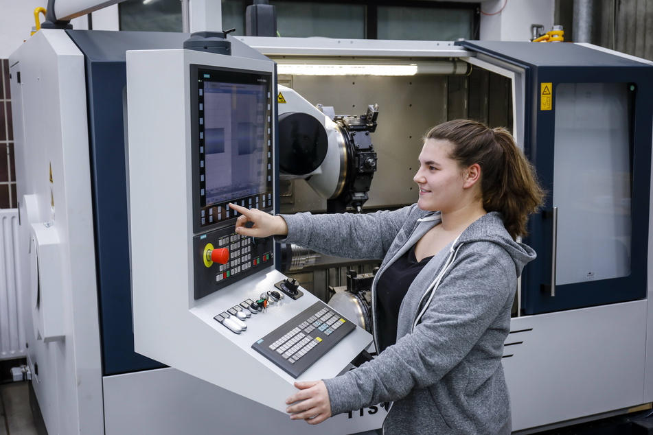 Eine junge Frau an einer CNC-Werkzeugmaschine. Man hat es lange versäumt, auch Mädchen für handwerkliche und technische Berufe zu interessieren.