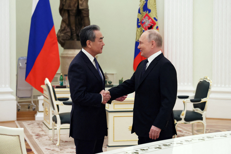 Russia's President Vladimir Putin shakes hands with China's Director of the Office of the Central Foreign Affairs Commission Wang Yi.