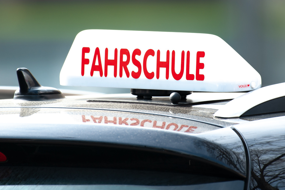 Ein Schild mit der Aufschrift "Fahrschule" ist auf einem Fahrschulauto befestigt.