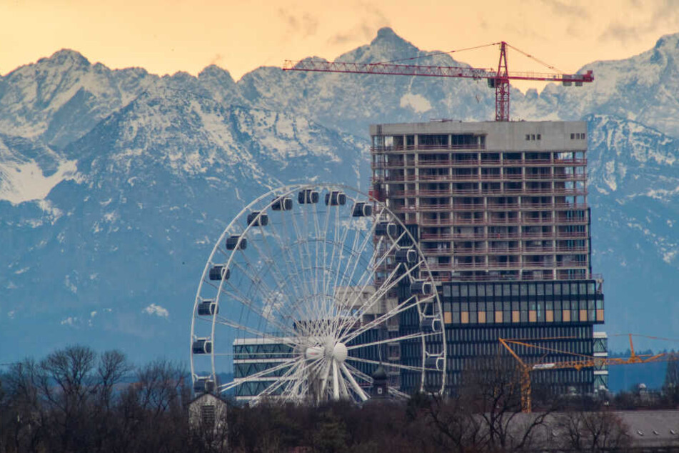 Das Riesenrad "Hi-Sky München" und ein sich im Bau befindliches Hochhaus sind bei einer Föhn-Wetterlage vor den mehr als 100 Kilometer entfernten Alpen zu sehen.