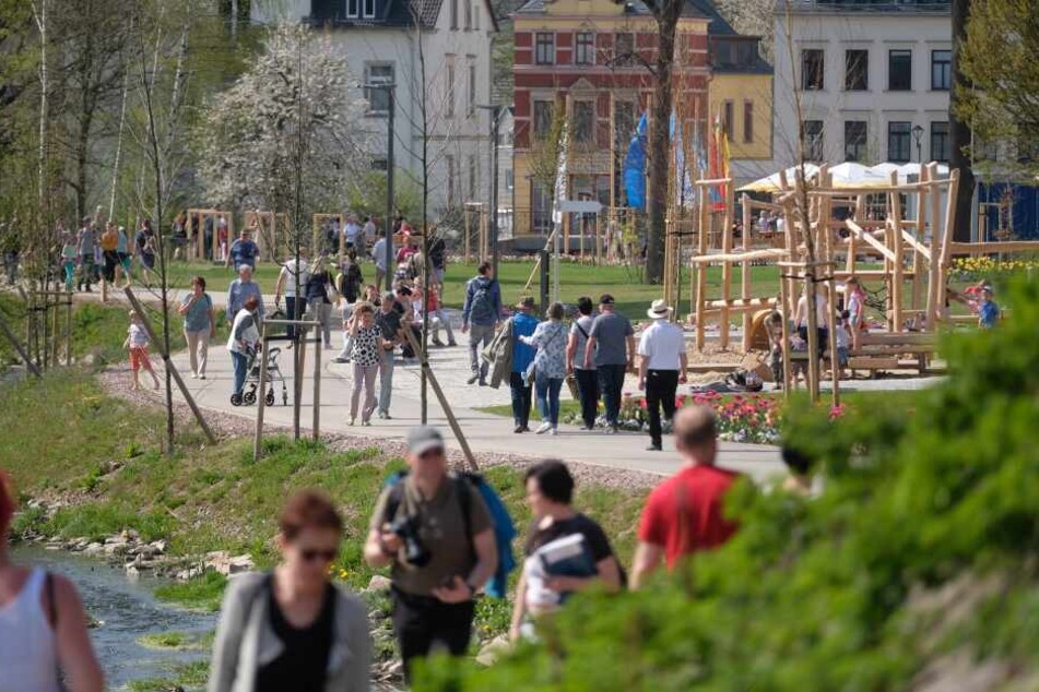 Besucher der sächsischen Landesgartenschau gehen über das Ausstellungsgelände am Mühlbach.