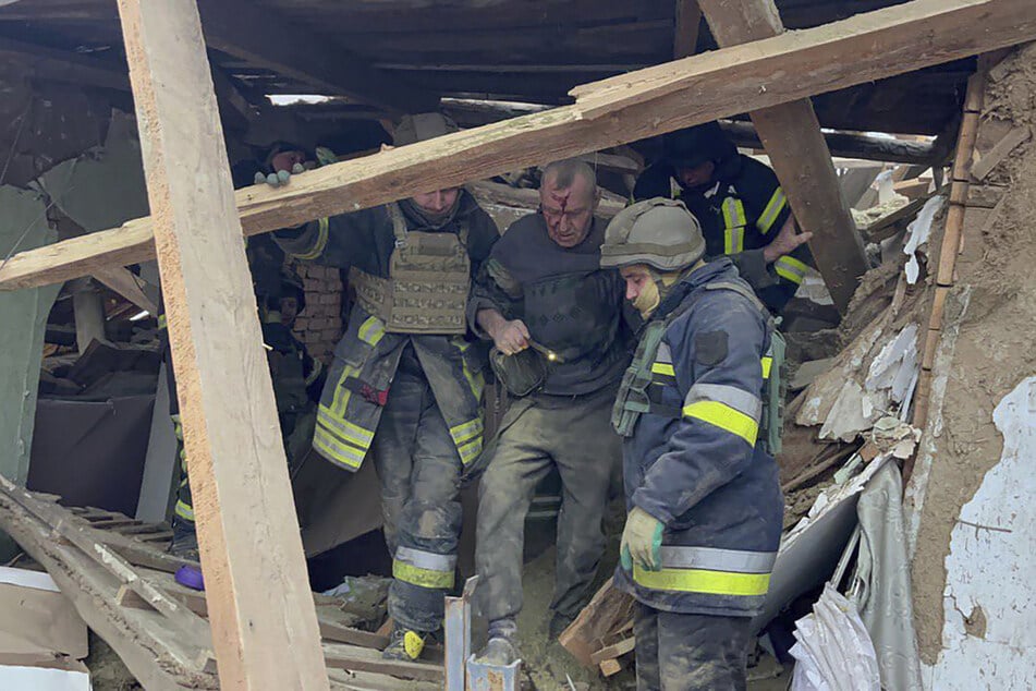 Rettungskräfte helfen einem verletzten Mann, nachdem sein Wohnhaus von einer russischen Rakete getroffen wurde.