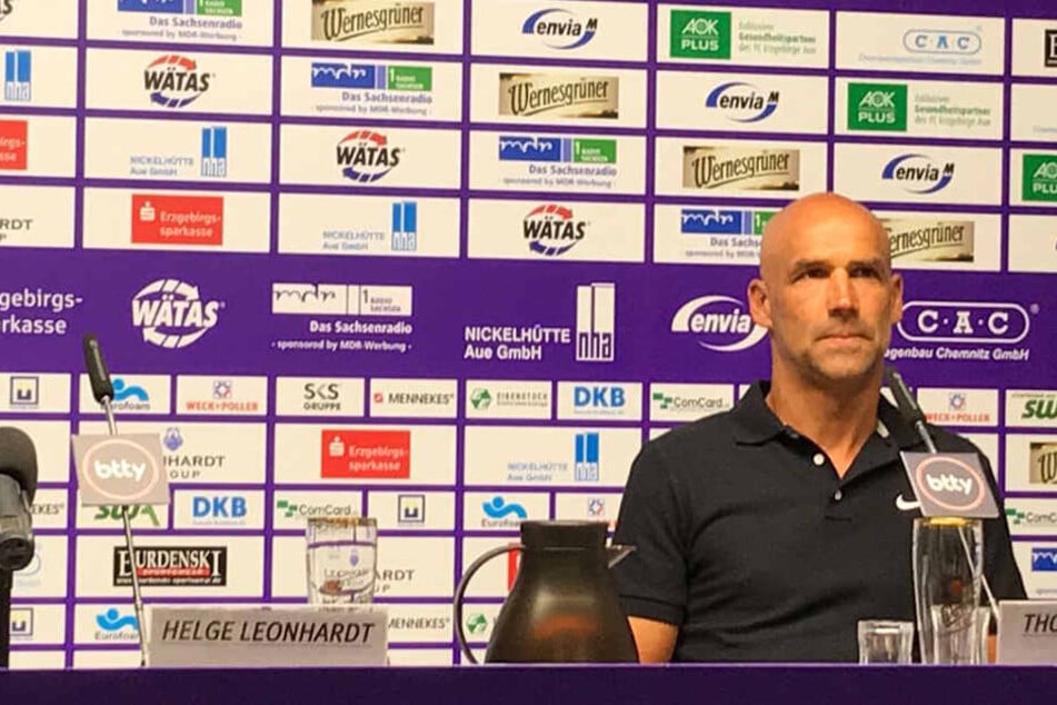 Der neue Aue-Trainer nimmt auf der Pressekonferenz den Platz auf dem Podium ein.