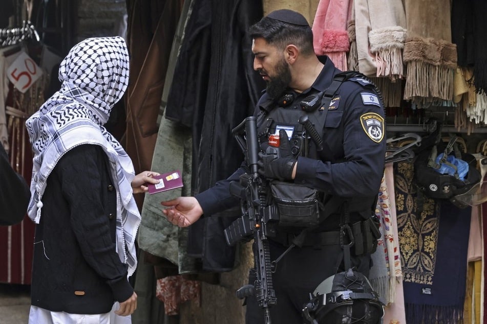 An Israeli soldier checks the identification of a Muslim devotee outside the Al-Aqsa mosque compound before the first Friday noon prayers of the Islamic holy fasting month of Ramadan in the Old City of Jerusalem on March 15, 2024.