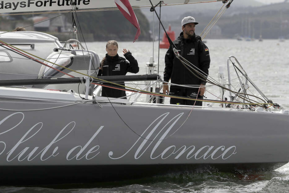 Greta Thunberg (l), Klimaaktivistin aus Schweden, und Skipper Boris Herrmann winken von Board der Hochseejacht "Malizia".