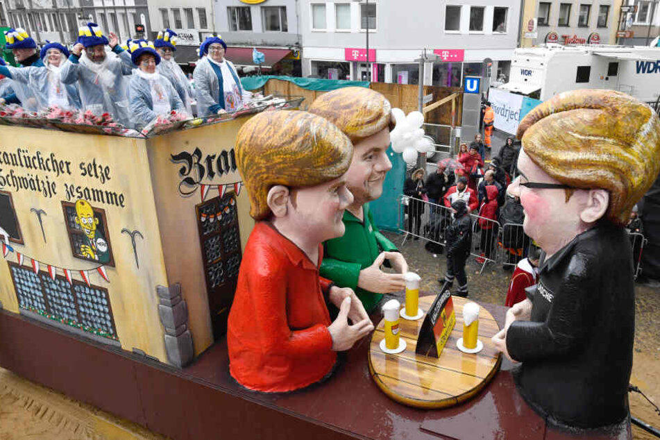 Köln: Ein Motivwagen des Rosenmontagszugs zeigt einen "Kanzlerstammtisch", an dem Armin Laschet (CDU, r), der Grünen-Vorsitzende Robert Habeck (M) und Finanzminister Olaf Scholz (SPD) sitzen