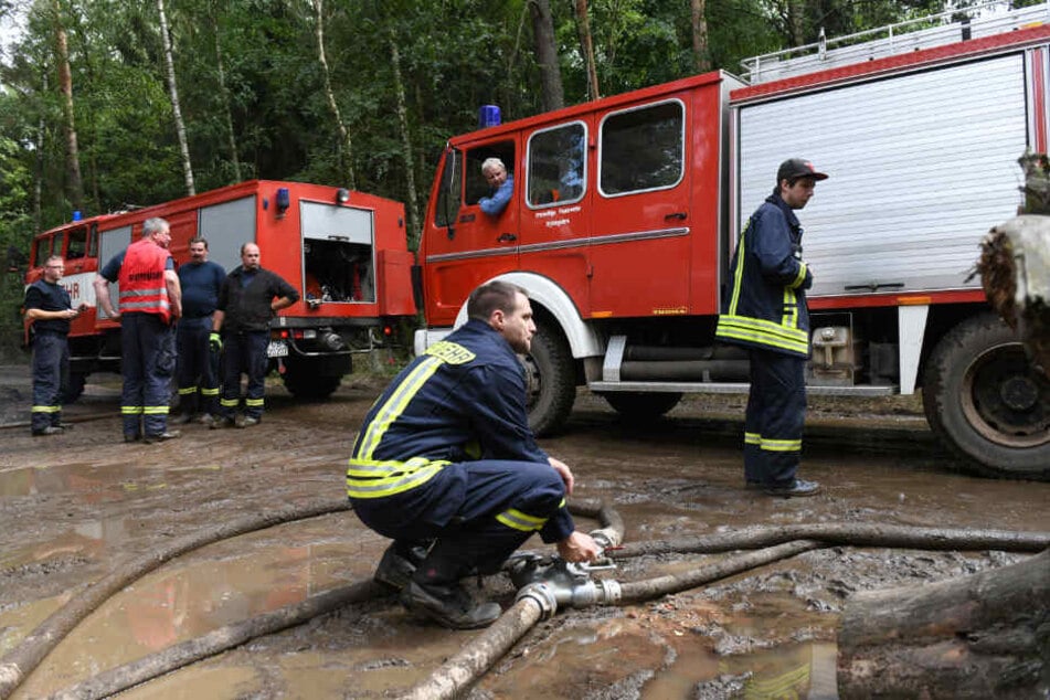 Feuerwehrmänner legen im Wald Schlauchverbindungen.
