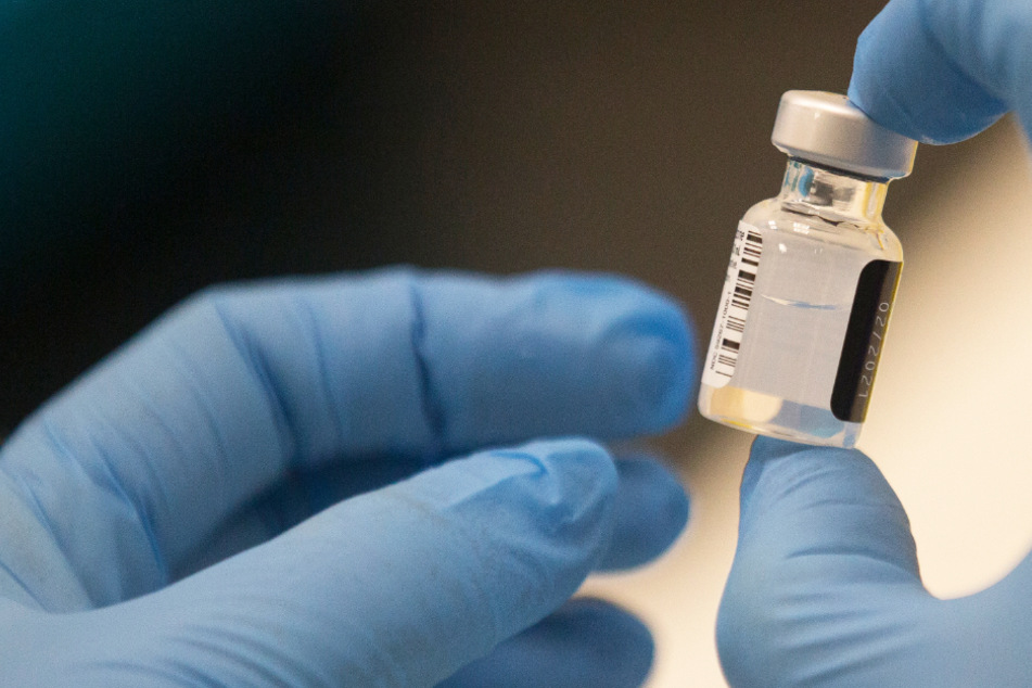 Ein Arbeiter hält eine Ampulle des Pfizer-BioNTech COVID-19-Impfstoffs in der Hand.