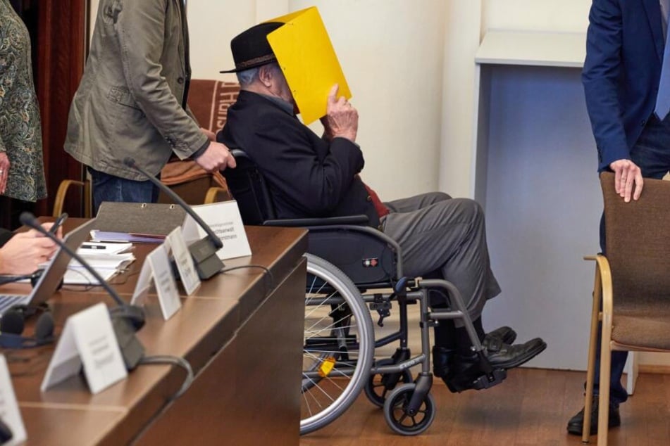 Der Angeklagte wird vor Beginn des Prozesses in einem Rollstuhl in den Gerichtssaal gebracht.