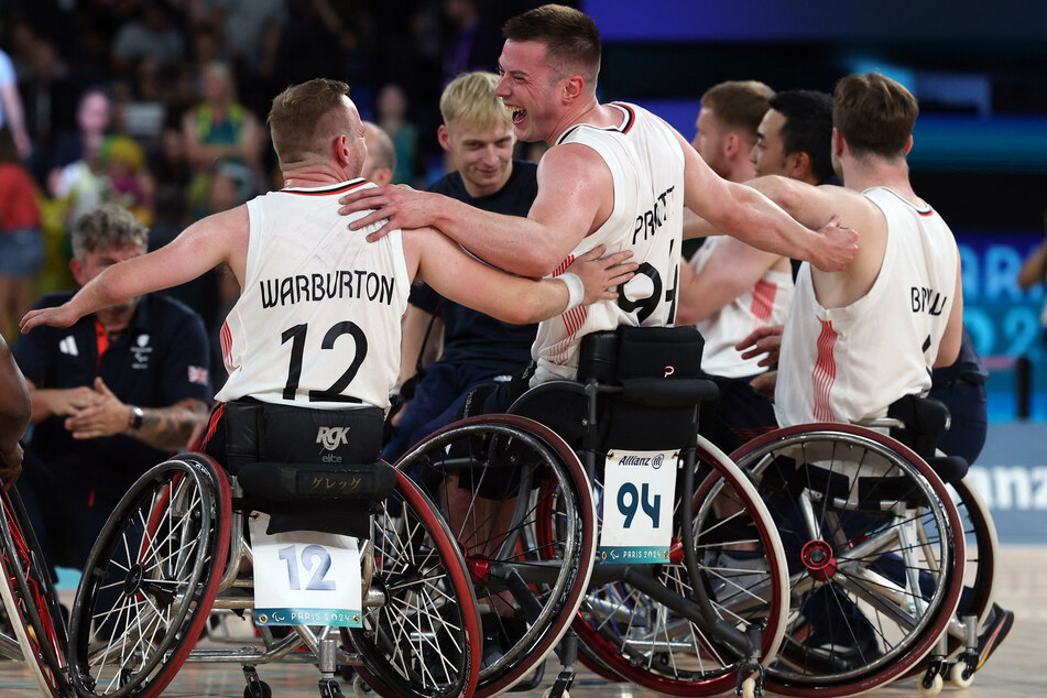 Gregg Warburton of Britain and Philip James Pratt of Britain celebrate with teammates after winning their wheelchair basketball men's quarter-final at the Paris Paralympics.