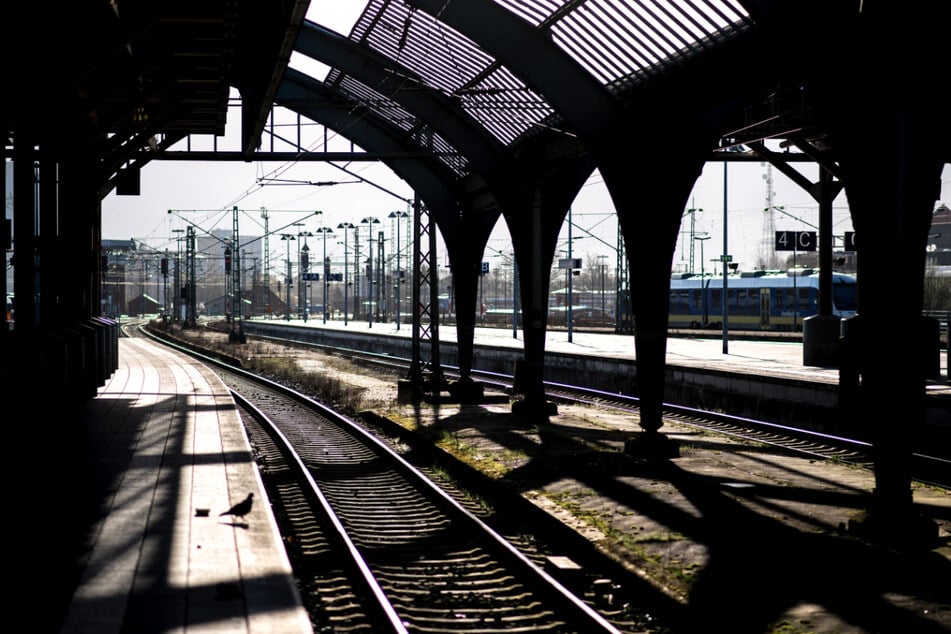 Mann sitzt mit baumelnden Beinen am Bahnsteig und wird von Güterzug erfasst