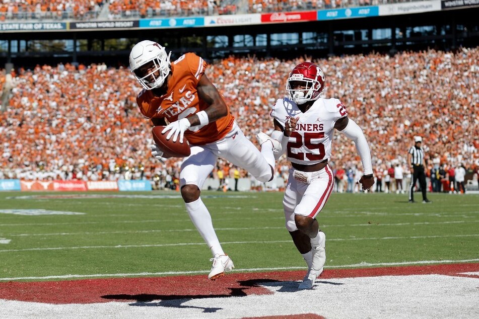 Joshua Moore of the Texas Longhorns catches a pass for a touchdown while defended by Justin Broiles of the Oklahoma Sooners in the first quarter during the 2021 AT&amp;T Red River Showdown.