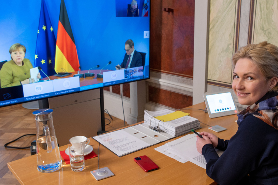Schwerin: Manuela Schwesig (SPD), die Ministerpräsidentin von Mecklenburg-Vorpommern, sitzt in der Staatskanzlei bei der Video-Schaltkonferenz zur Entwicklung der Corona-Pandemie vor einem Monitor, auf dem Bundeskanzlerin Angela Merkel (CDU) und Michael Müller (SPD), der Regierende Bürgermeister von Berlin, zu sehen sind.