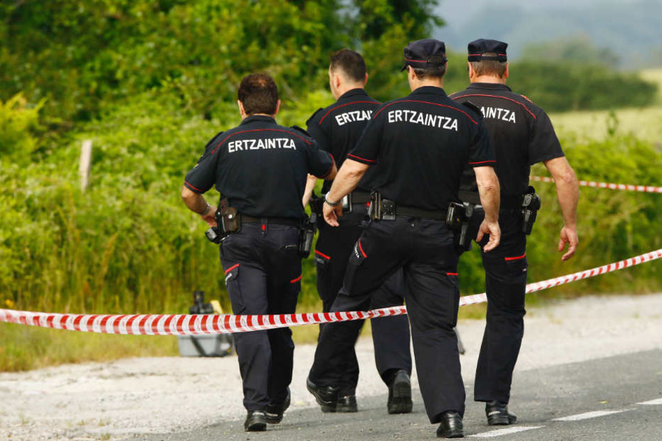 Beamte der baskischen Autonomiepolizei Ertzaintza klettern im Gemeindegebiet Asparrena über eine Absperrung. Sie fanden die Frauenleiche am Donnerstag unweit einer Tankstelle.
