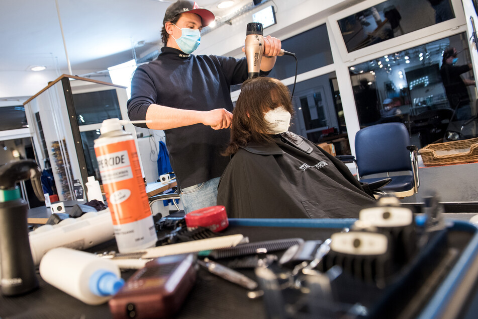 Henry Riehl, Friseur, föhnt einer seiner ersten Kunden nach der Wiedereröffnung, kurz nach Mitternacht die Haare.