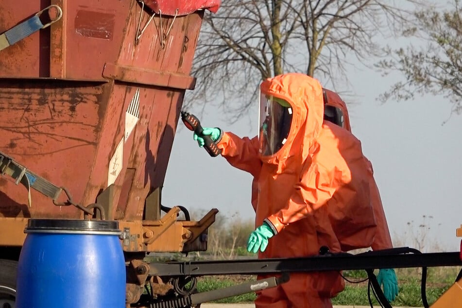 In Chemikalien-Ganzkörperanzügen kümmerten sich Kameraden um die ausgelaufene Flüssigkeit und den leckgeschlagenen Container.