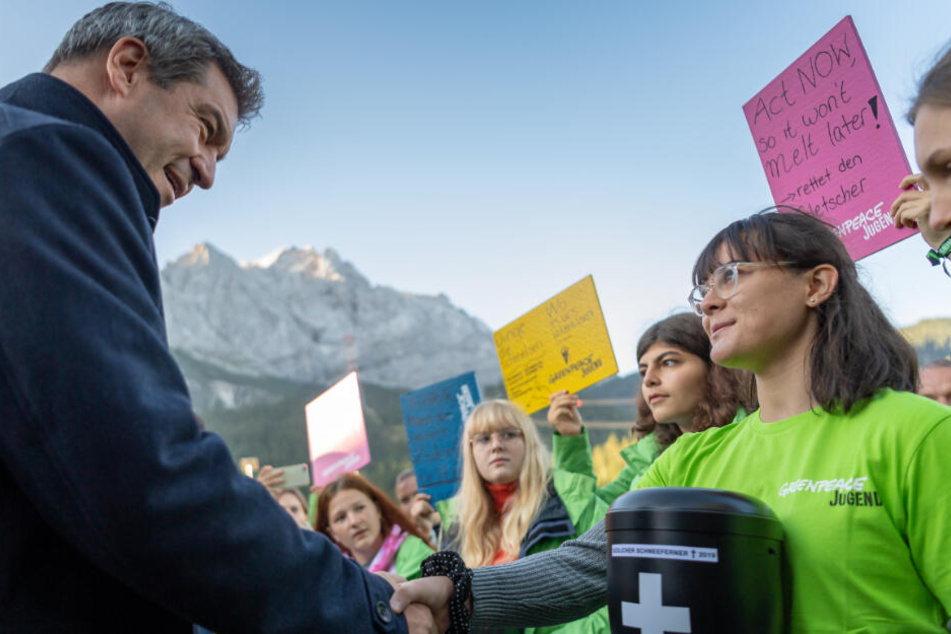 Markus Söder unterhält sich vor Beginn seiner Klimatour in der Zugspitzregion mit jugendlichen Greenpeace Aktivisten.