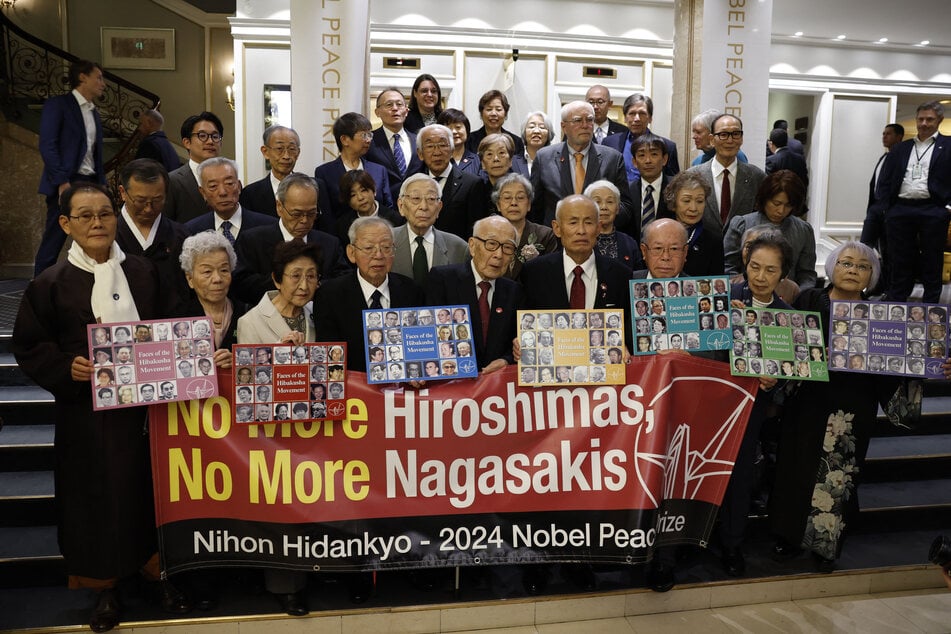 Hibakushas, survivors of the nuclear attacks on Hiroshima and Nagasaki, pose with a banner reading "no more Hiroshima, no more Nagasaki," before attending later as guests the Nobel Peace Prize award ceremony at the Oslo City Hall in Oslo, Norway on December 10, 2024.