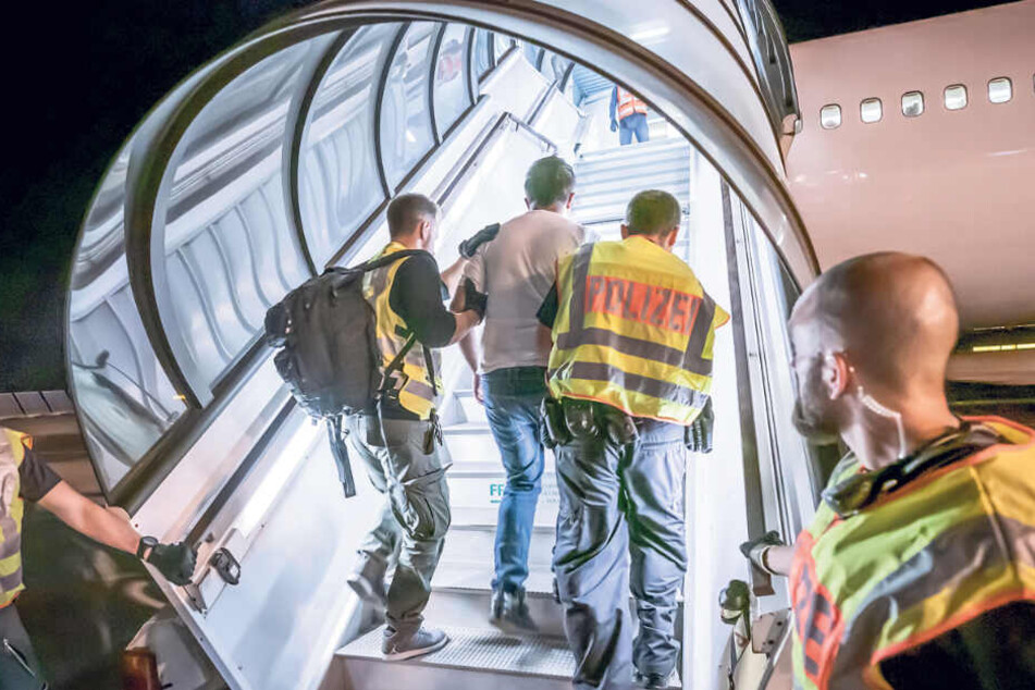 Polizeibeamte führen einen Afghanen die Gangway zum Charterflugzeug hinauf.