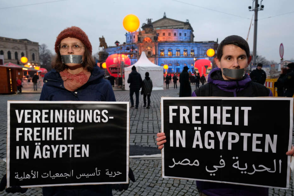 Aktivisten von Amnesty International stehen mit Transparenten während einer Demonstration vor der Semperoper.