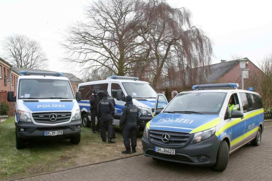 Einsatzkräfte der Polizei stehen vor einem Haus, in dem die Männer festgenommen wurden.