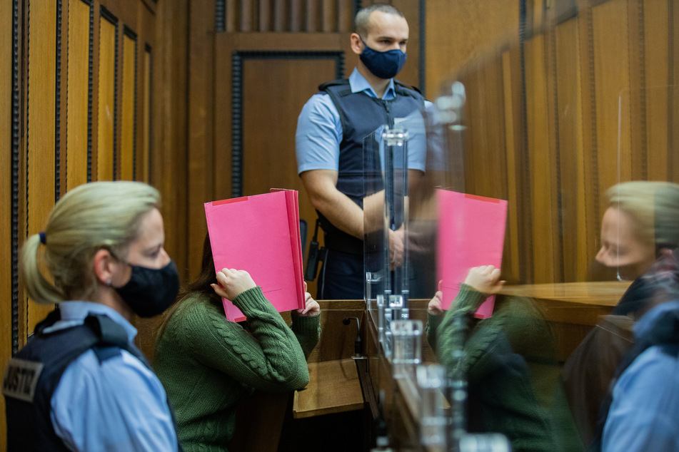 Die Angeklagte sitzt in einem Gerichtssaal des Landgerichts zwischen Justizvollzugsbeamten.