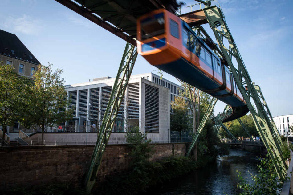 Eine Schwebebahn fährt am Justizzentrum in Wuppertal vorbei.