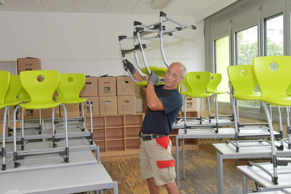 Während die Schüler ihre Sommerferien genießen, schleppt Umzugsmitarbeiter Ralf Erben (57) Bänke und Stühle.
