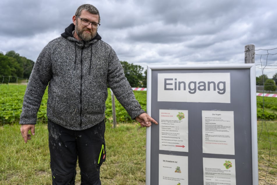 Am Eingang der Erdbeerplantage von Familie Funck weist nun ein Schild auf die neuen Regeln beim Betreten des Feldes hin, erklärt Verkäufer Mario Thiele (47).