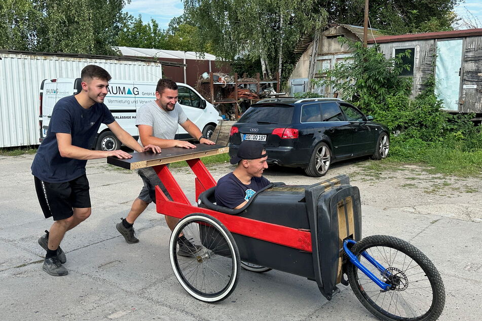 Tim Lauter (22, l.) und John Gebhard (24, Mitte) schieben den "GlasfaserRacer" mit Domenic Wachs (24) beim Testlauf an.