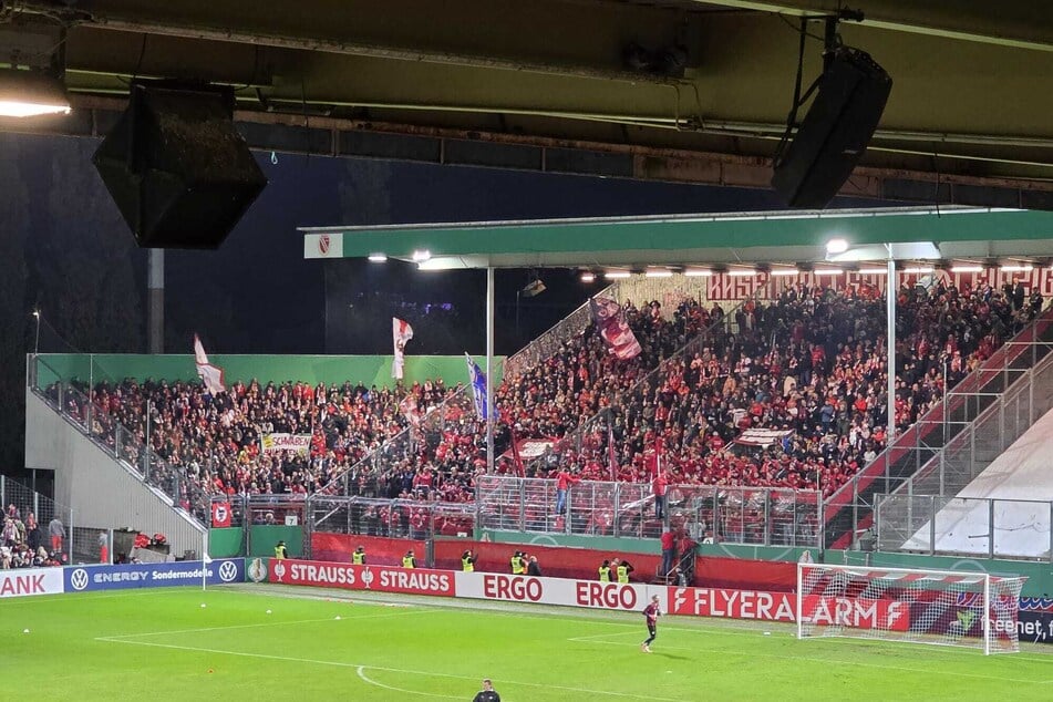 Auch im Gästeblock schwingen die ersten Fahnen.