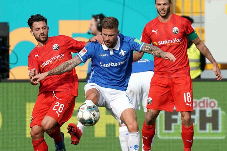 Tobias Kempe (M) sichert gegen Dennis Diekmeier (r) und Besar Halimi (l) aus Sandhausen den Ball.