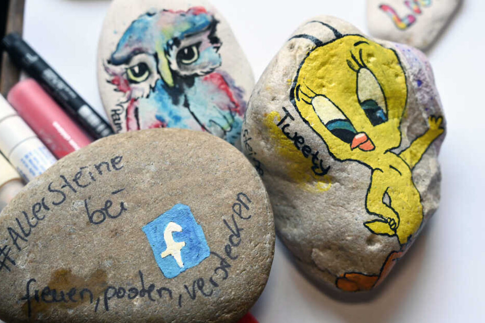 Von Mitgliedern der Facebook-Gruppe "#Allersteine" bemalte Steine liegen auf einem Tisch.
