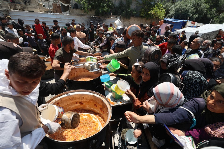Palestinians queue for a portion of hot food distributed by a charity kitchen at the Nuseirat refugee camp in the central Gaza Strip on Monday.