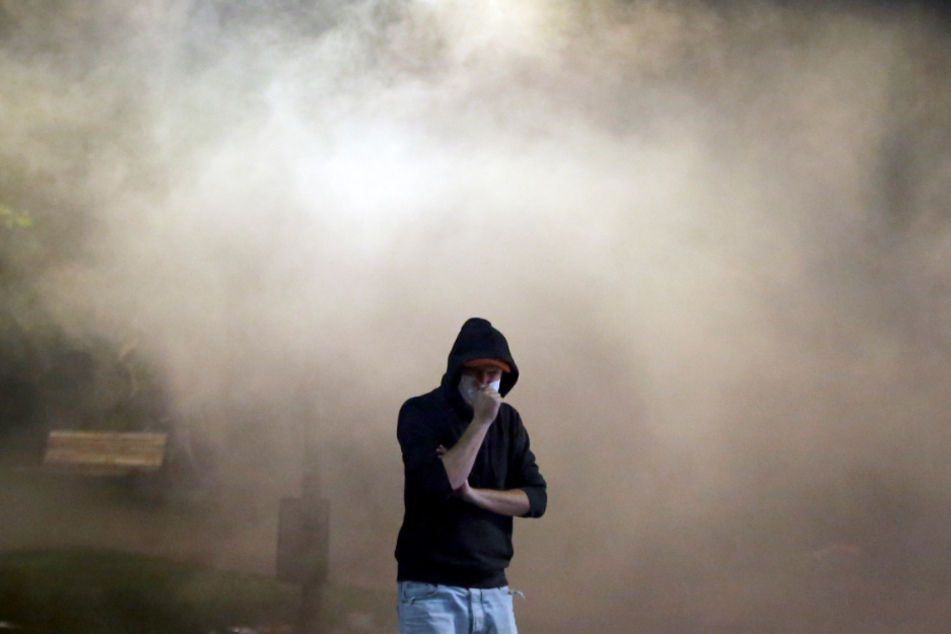 Ein Demonstrant steht während eines Protests gegen die Ankündigung des serbischen Präsidenten protestieren, wieder striktere Corona-Einschränkungen einzuführen, nachdem erneut hohe Todeszahlen gemeldet wurden, in einer Wolke aus Tränengas.