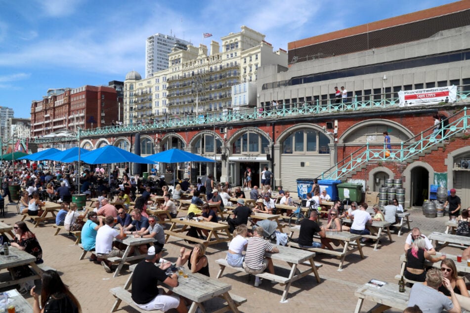 Brighton: Viele Menschen machen es sich auf einer Strandpromenade samt Bar gemütlich.