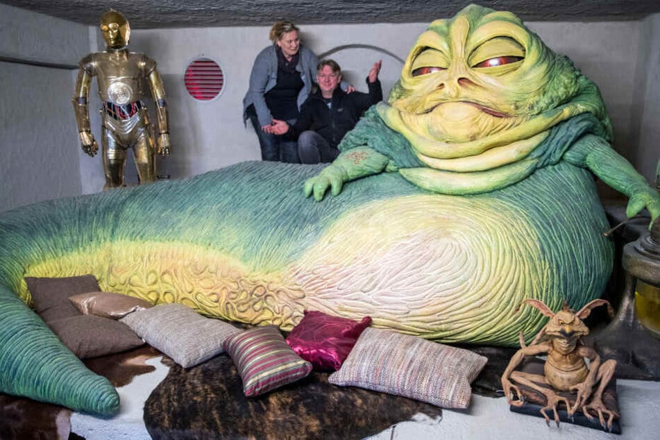 Die StarWars-Fans und Gründer des Fanprojekts "Outpost One", Kirstin und Marc Langrock, stehen neben der Nachbildung der Kinofigur "Jabba" in einem der 29 nachgebildeten Set-Szenen aus unterschiedlichen Filmen der Star Wars Serie.