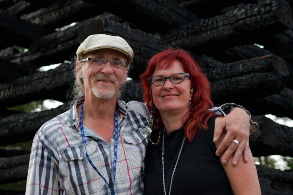 Das Ehepaar Birgit und Horst Lohmeyer steht vor einem Mahnmal bestehend aus den verkohlten Balken ihrer abgebrannten Scheune.