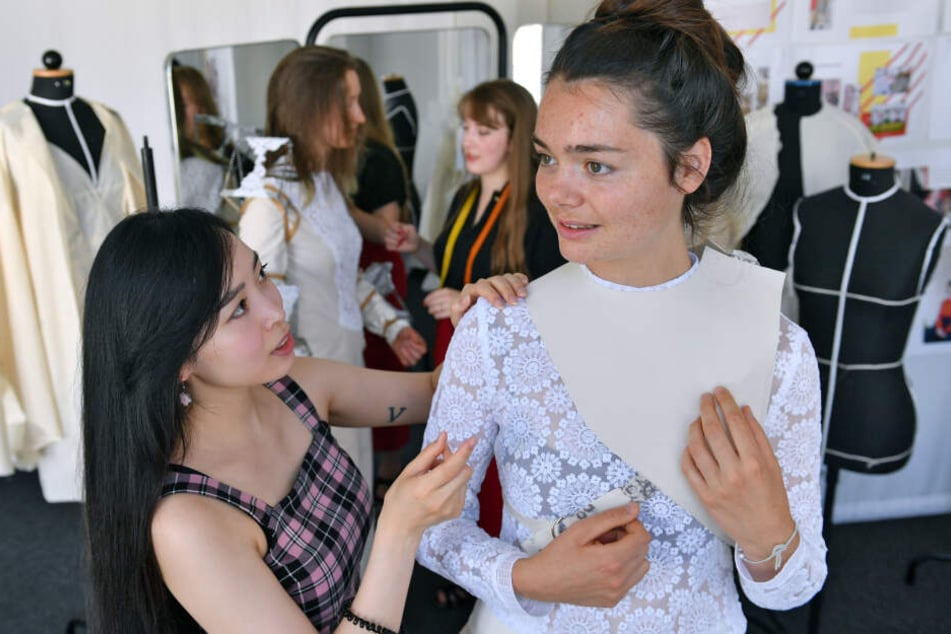 Thuy Tien Phan (l.) und Juliane Mann, Modedesign-Studentinnen der Vitruvius-Hochschule in Leipzig, präparieren ein Outfit mit Stickereien aus Plauener Spitze.